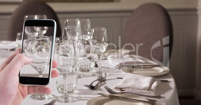 Hand photographing wine glasses through smart phone at bar