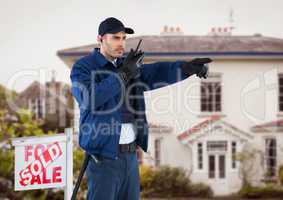 Security guard talking on walkie talkie and gesturing while standing by sign board against house
