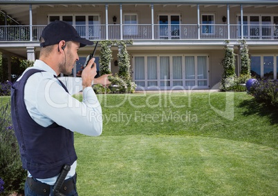 Security guard talking on radio while pointing at house