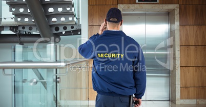 Rear view of security guard waiting for lift while standing in office building