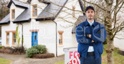 Security guard with arms crossed standing on road against house