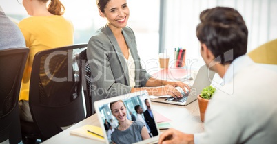 Businessman video conferencing while looking at executive in office