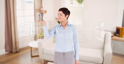 Businesswoman holding gift while standing in room against sofa