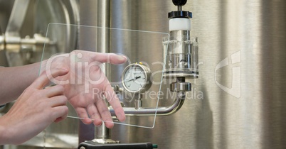 Hands photographing machinery through transparent device at brewery
