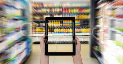 Cropped hands photographing products through digital tablet at supermarket