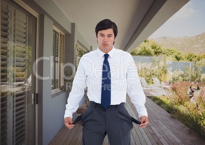 Businessman showing empty pockets outside house