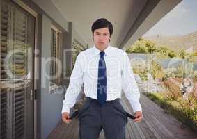 Businessman showing empty pockets outside house