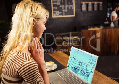 young woman in coffee shop with laptop, on the screen the draw of the new design to the office (two-