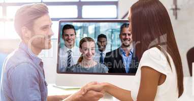 Business people shaking hands while video conferencing with colleagues