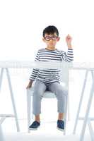 Boy sitting on chair against white background