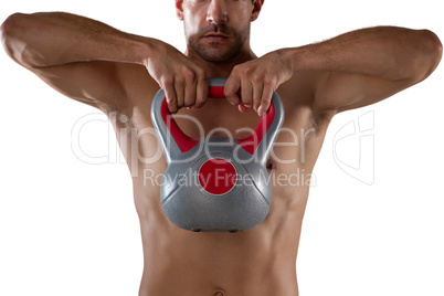 Midsection of shirtless sports player lifting kettle bell Midsection of shirtless sports player lifting kettle bell