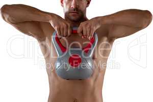 Midsection of shirtless sports player lifting kettle bell
