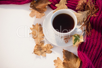 Cup of black tea with autumn leaves and woolen cloth