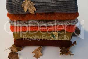 Stack of woolen clothing with autumn leaves