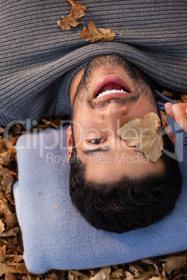 Overhead of man lying on autumn leaves