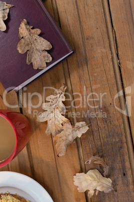 Coffee mug, autumn leaves and diary on wooden table