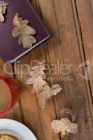 Coffee mug, autumn leaves and diary on wooden table