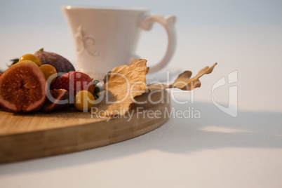 Autumn leaves, various fruits and cup of tea on chopping board