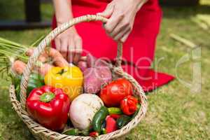 Woman holding a basket of fresh vegetables at stall