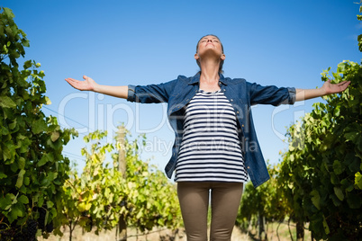 Beautiful vintner standing with arms outstretched in vineyard