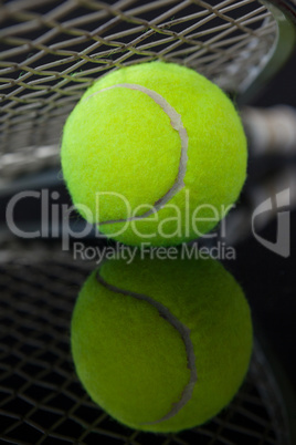 Close up of tennis racket on fluorescent yellow ball with reflection
