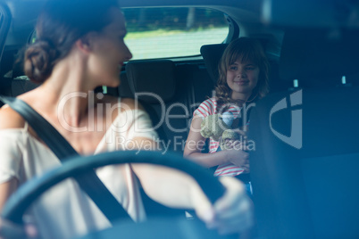 Woman driving a car while daughter sitting in the backseat of car