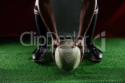 Low section of rugby player holding ball while standing against Italian Flag