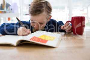 Boy as business executive writing in a book