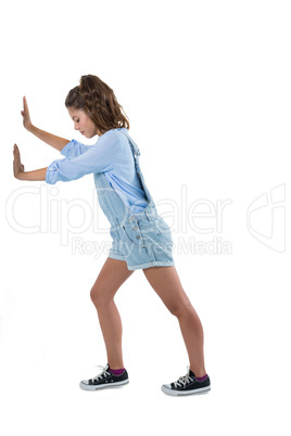 Teenage girl pushing against white background