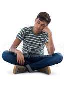 Teenage boy relaxing against white background