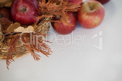 Overhead of red apples with autumn leaves in wicker basket