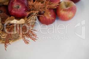 Overhead of red apples with autumn leaves in wicker basket