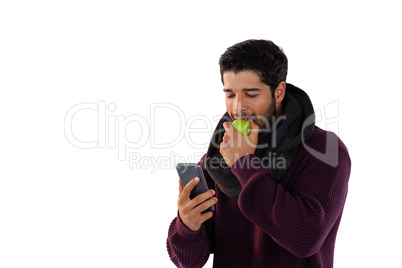 Man eating apple while using mobile phone