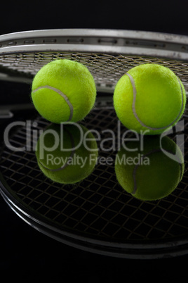 Close up of fluorescent yellow tennis balls with racket with reflection