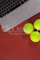 Overhead view of tennis balls by laptop