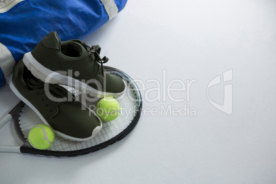 Sports shoe and tennis balls on racket by bag