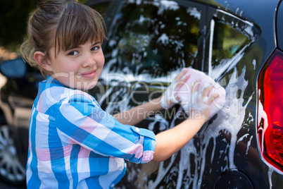 Teenage girl washing a car on a sunny day