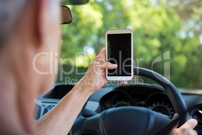 Senior woman using mobile phone while driving a car