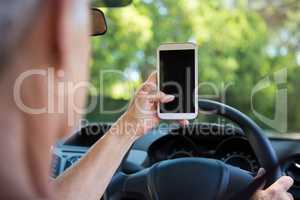 Senior woman using mobile phone while driving a car