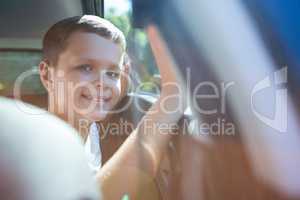 Happy Teenage boy sitting in the back seat of car