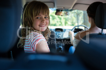 Teenage girl sitting in the back seat while woman driving a car