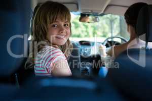 Teenage girl sitting in the back seat while woman driving a car