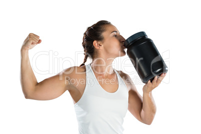Female athlete flexing muscles while kissing supplement jar