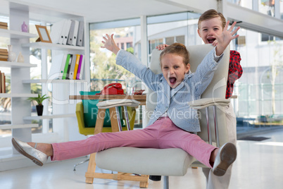 Boy as business executives pushing his colleague on chair