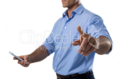Male executive pressing an invisible virtual screen while using mobile phone