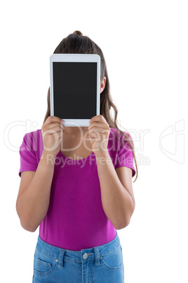 Teenage girl hiding her face behind digital tablet