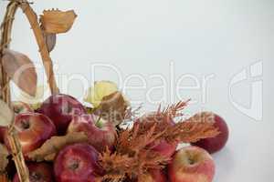Close-up of red apples with autumn leaves in wicker basket