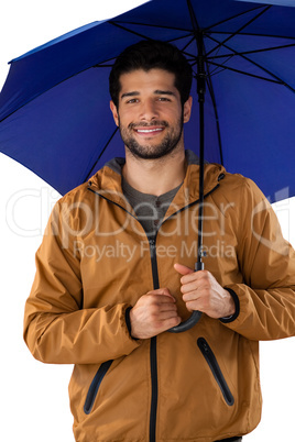 Smiling man standing under umbrella against white background