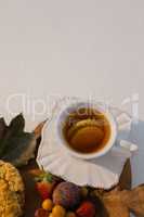 Various fruits, autumn leaves and cup of green tea on chopping board