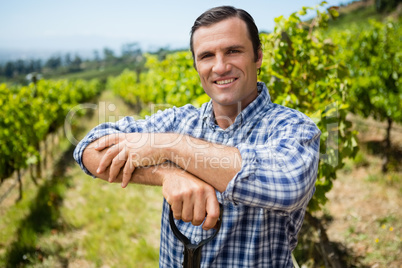 Portrait of vintner standing with shovel in vineyard